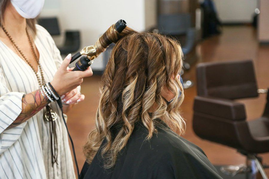 Penata rambut membuat gelombang rambut dengan catok di salon